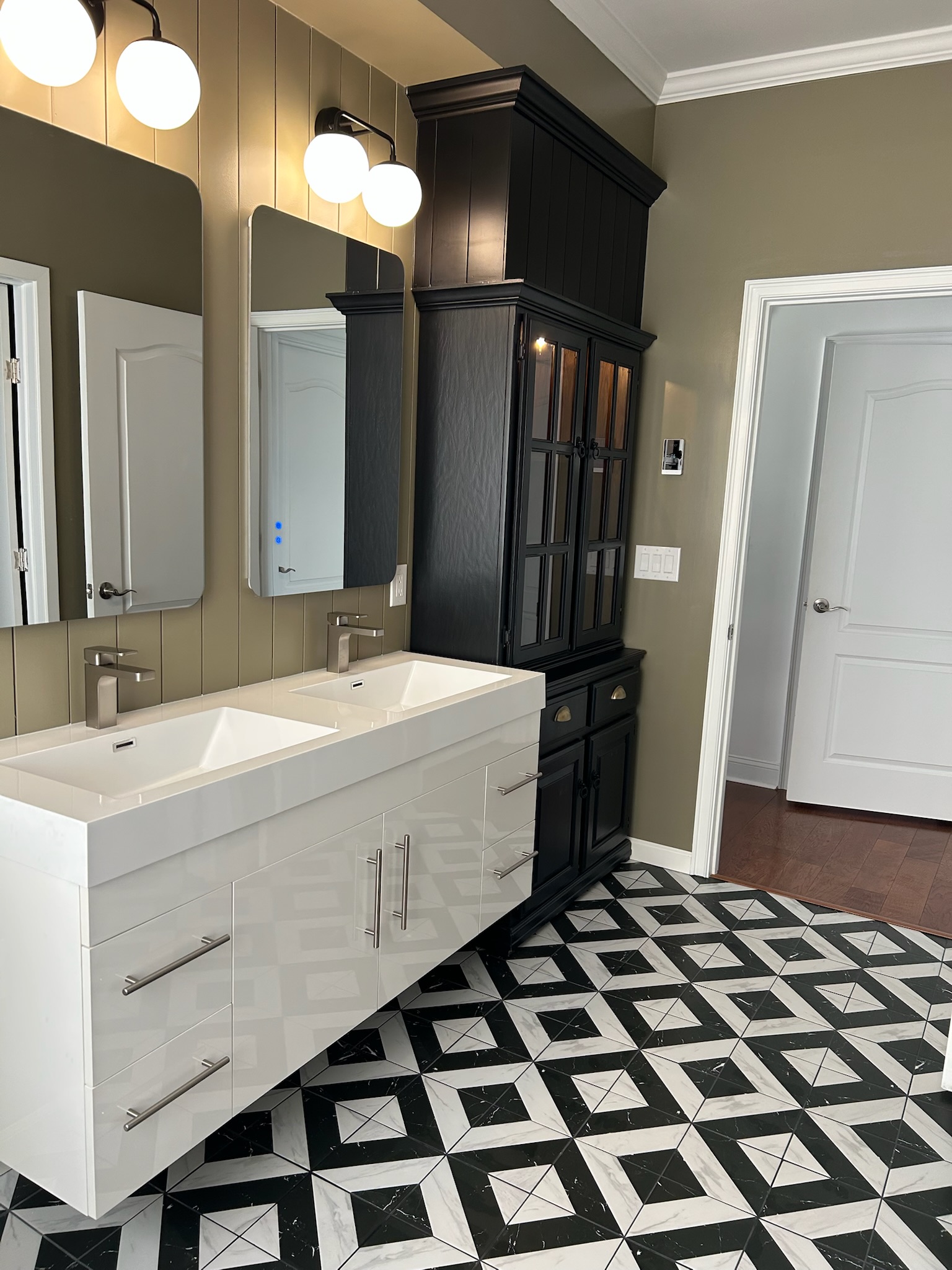 Floating white double-trough vanity and tall black linen tower with glass-front cabinet in geometric-tile master bath