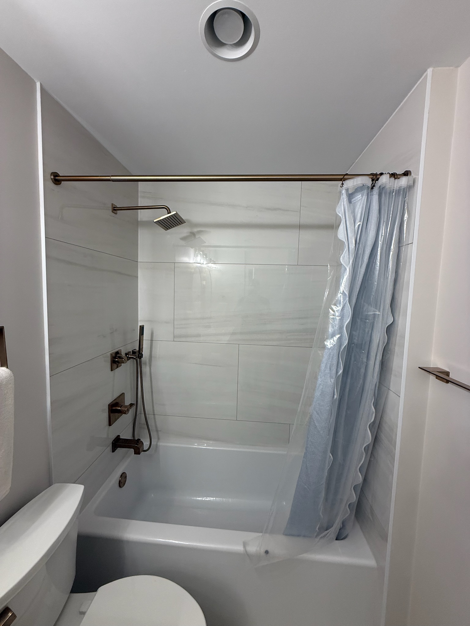 Tub-shower combo with large-format white marble-look porcelain tile and brushed brass fixtures in Upstate SC
