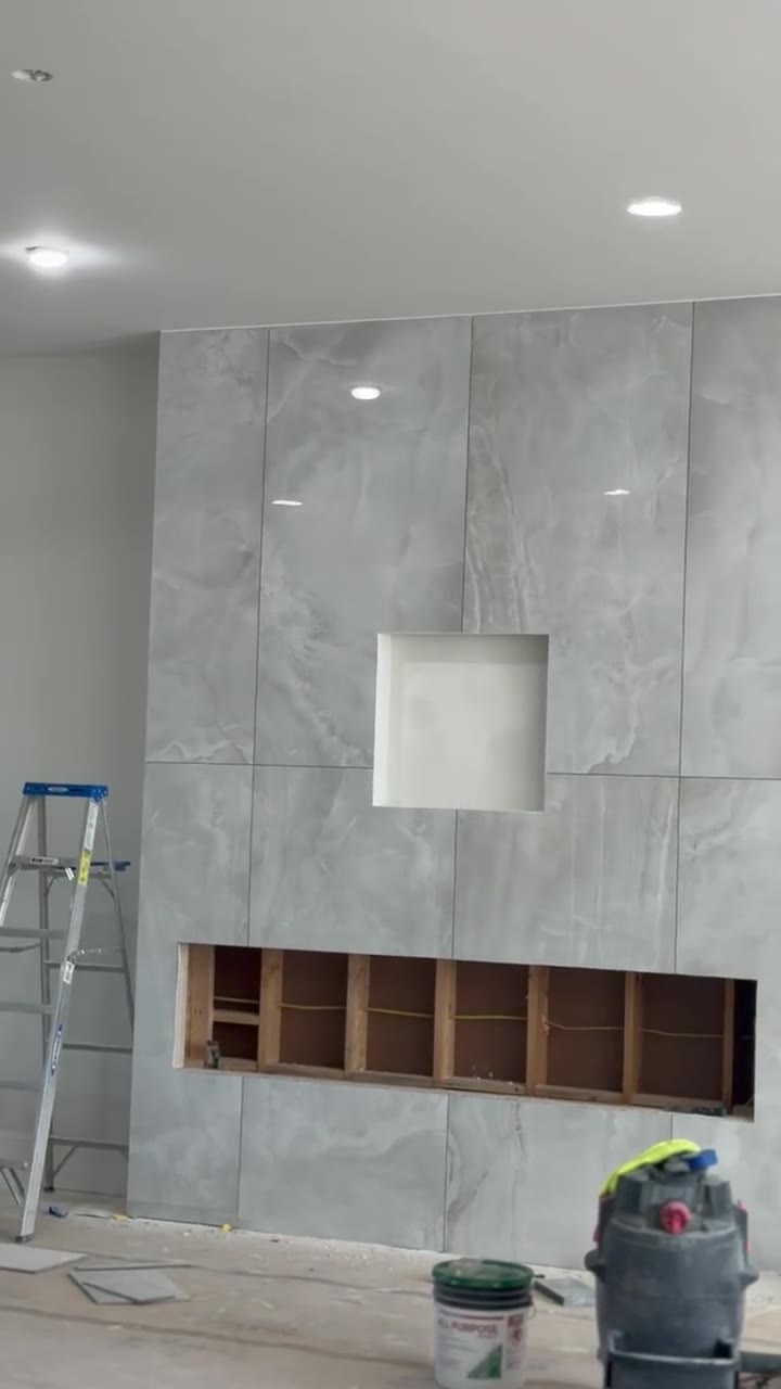 Large-format marble-look porcelain slab feature wall with recessed niche taking shape during a high-end build in Chesnee, SC